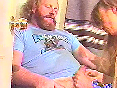 Two guys service a burly guy with a beard in a homemade video