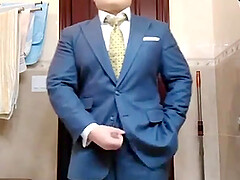 Сheerful business man fingering in a suit in front of a mirror